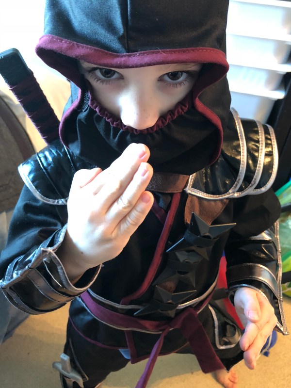 Child dressed in ninja costume doing a ninja pose.
